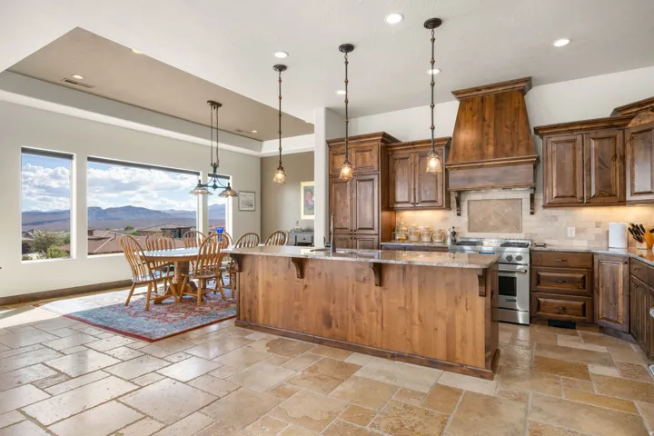 Gourmet kitchen featuring a wood island with pendant lighting, granite countertops, stainless steel appliances, and wood cabinetry