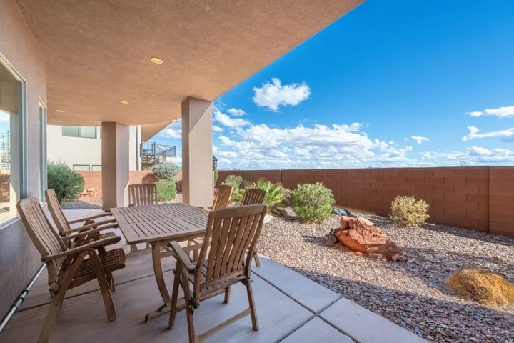 Covered patio with recessed lighting, concrete flooring, and a low-maintenance gravel landscape featuring a privacy wall