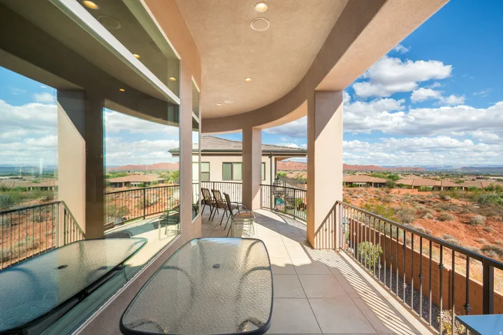 Curved balcony with recessed lighting, tile flooring, and metal railings, offering expansive desert scenery