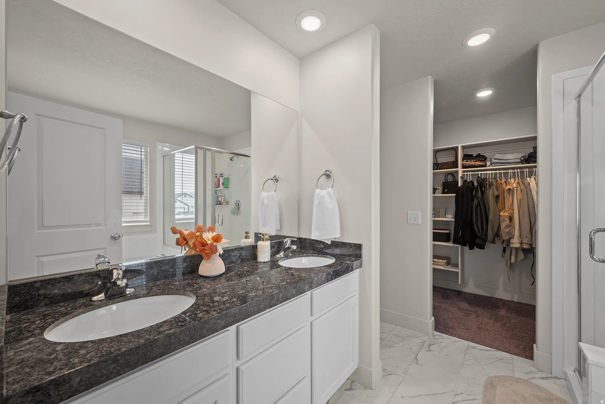 Dual vanity with dark stone countertop, white cabinetry, and undermount sinks