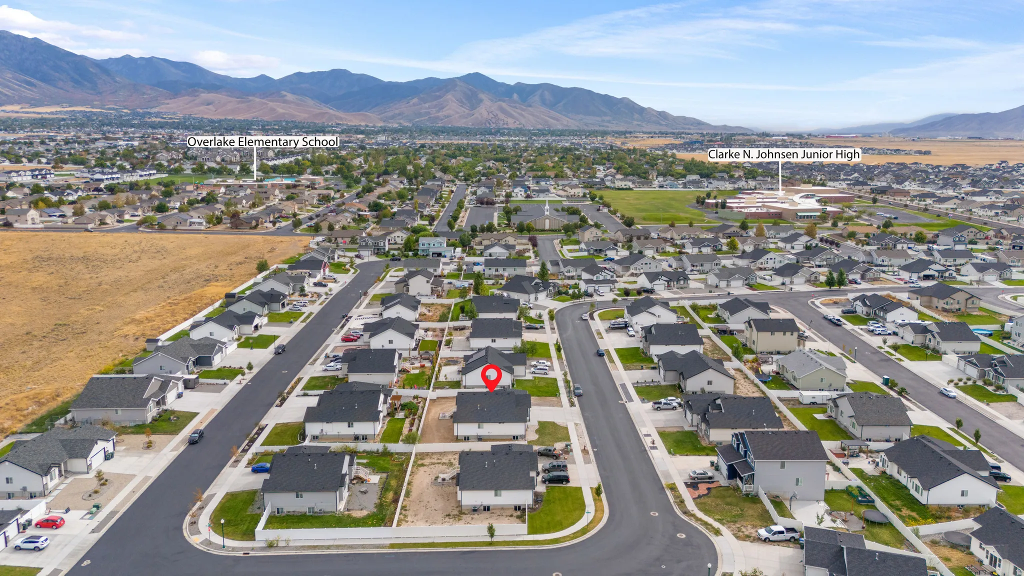 Community setting featuring residential streets, detached homes with dark roofs, and distant mountainous terrain