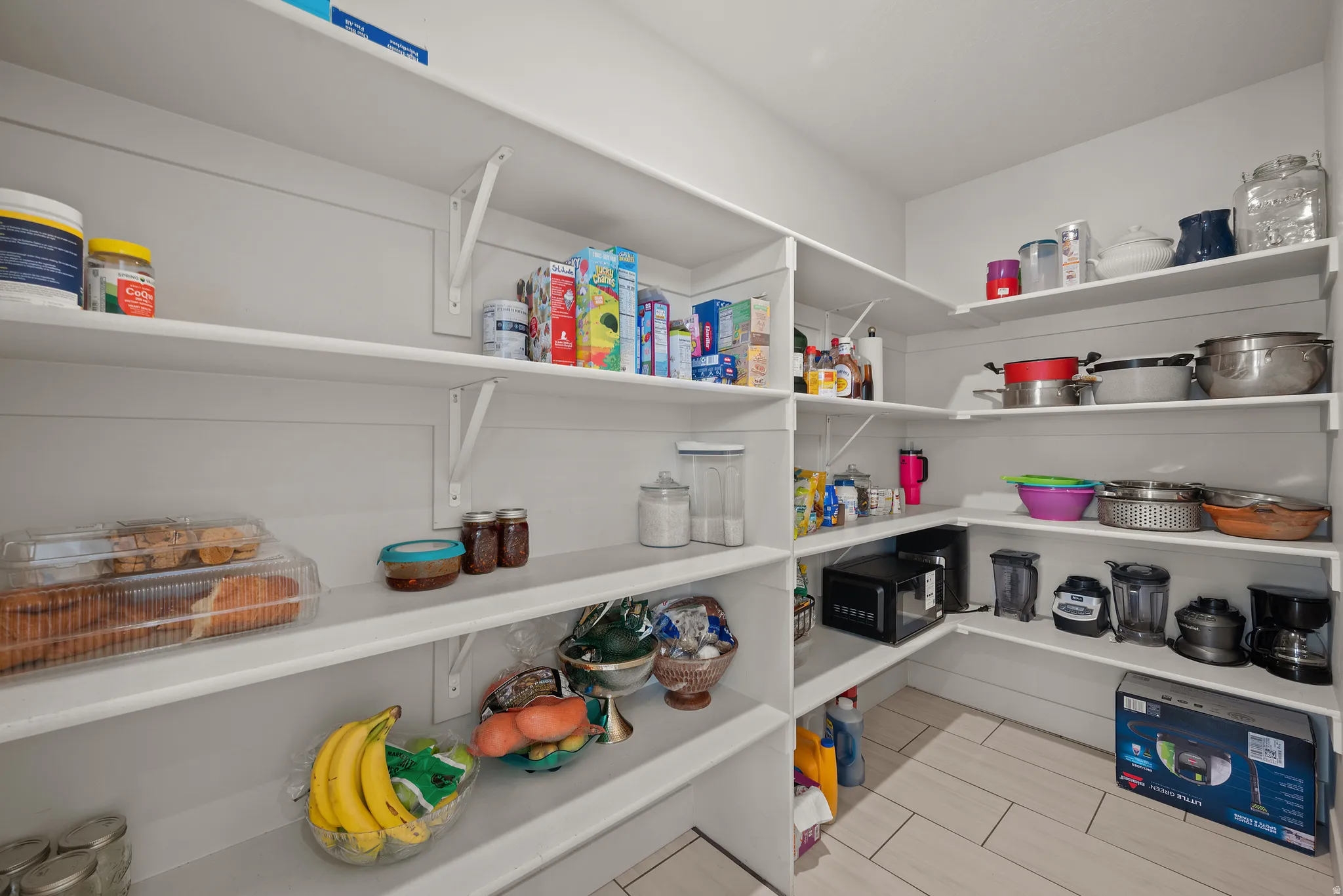 Expansive pantry with white shelving and tile flooring