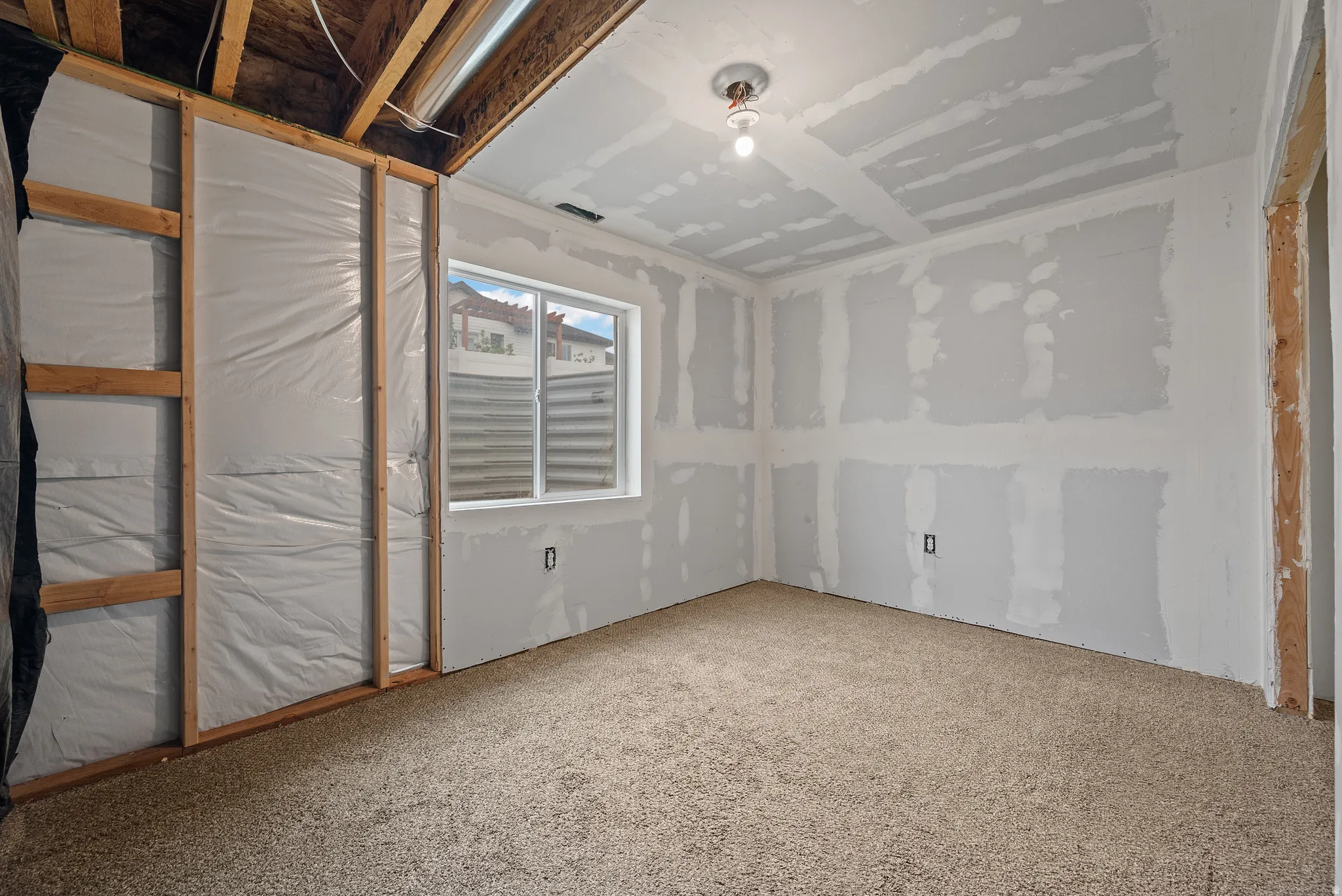 In-progress room featuring carpet flooring, a window, and exposed ceiling joists