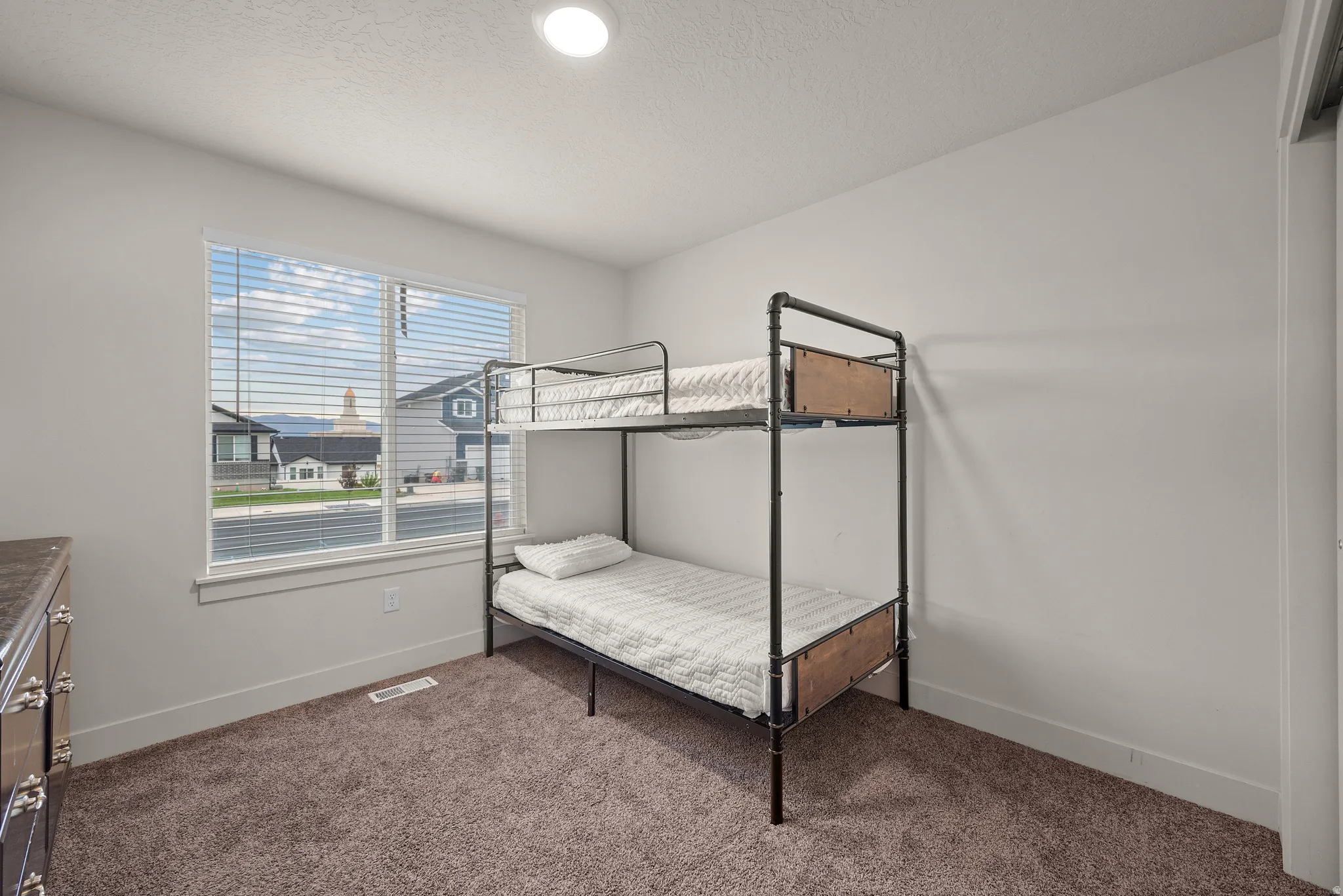 Recessed lighting fixture, window with blinds, and neutral carpet flooring