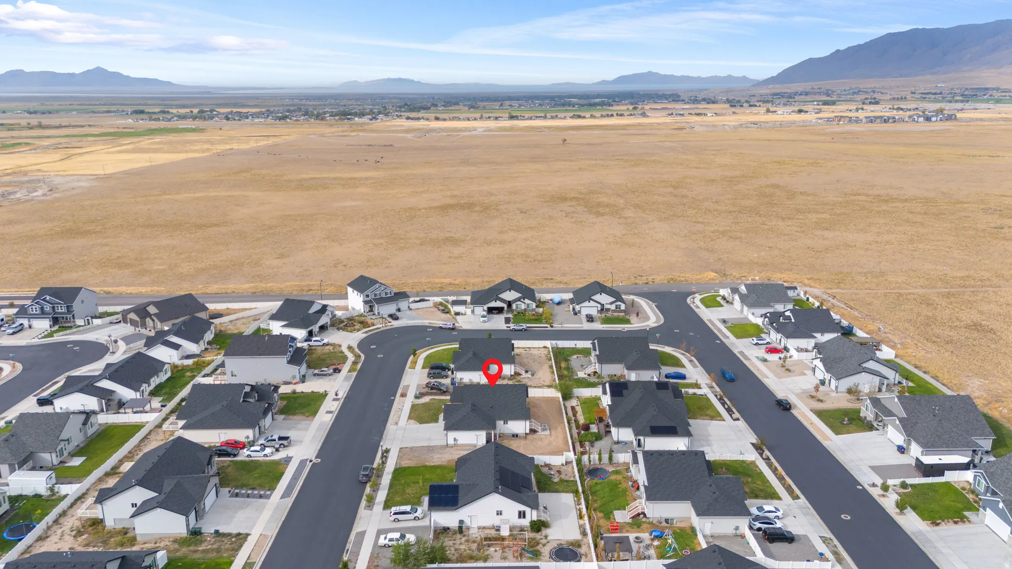 Residential development with newly paved streets and sidewalks, featuring multiple single-family homes with dark roofs and light-colored exteriors