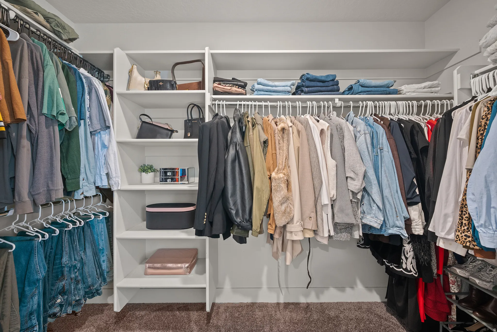 Built-in white shelving, multiple hanging rods, and an open layout
