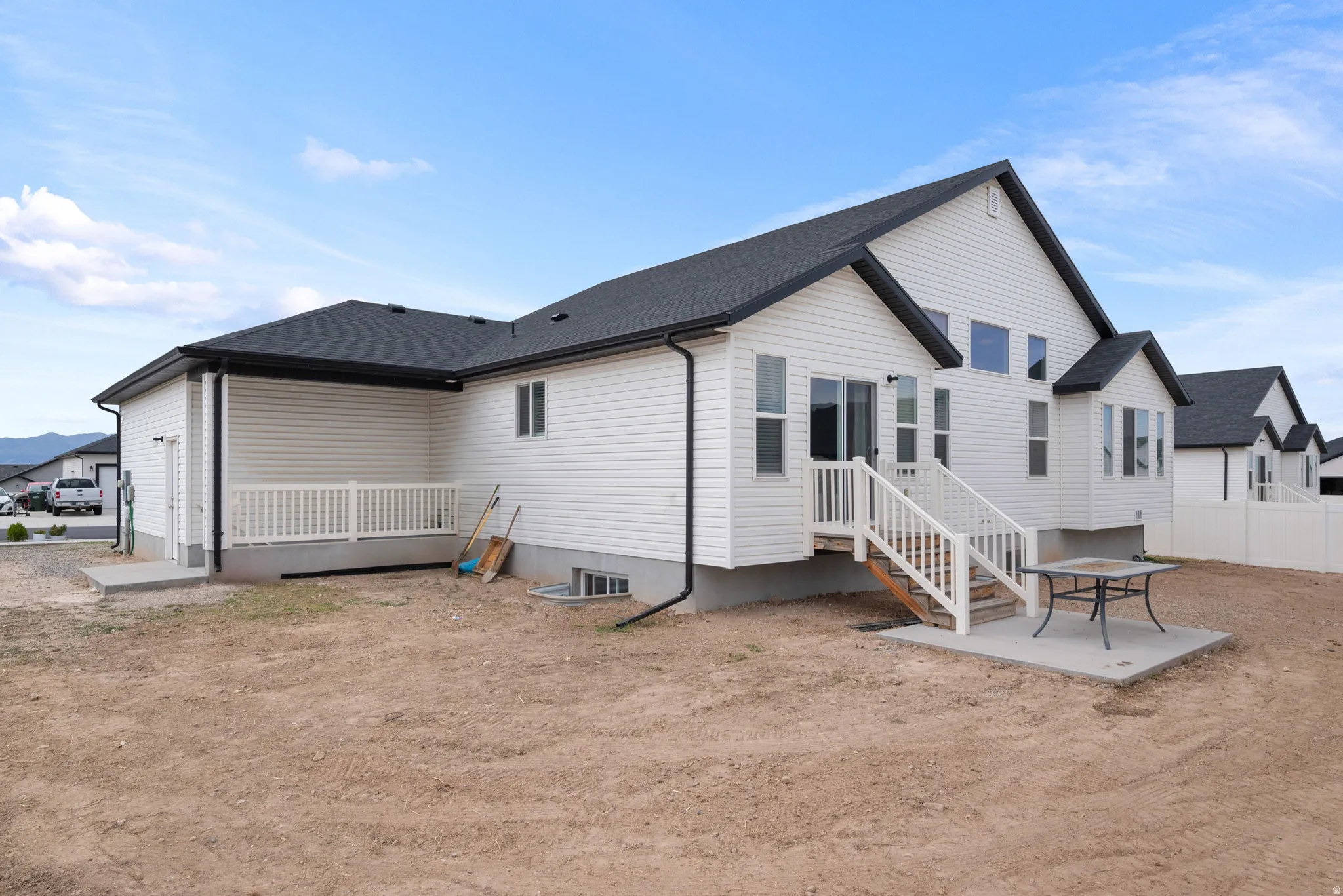 Modern ranch-style home featuring white vinyl siding, a peaked roof with dark asphalt shingles, and an attached garage with overhead door