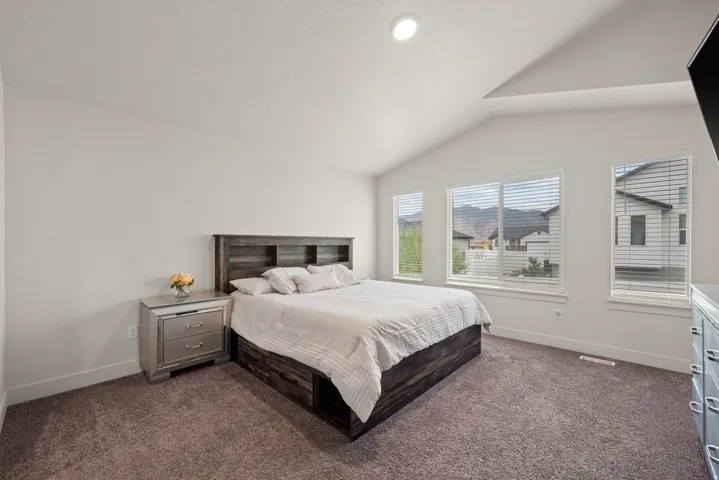 Vaulted ceiling bedroom with recessed lighting, wall-to-wall carpeting, and multiple windows
