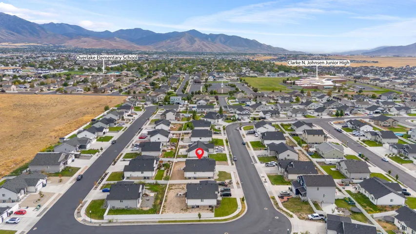 Community setting featuring residential streets, detached homes with dark roofs, and distant mountainous terrain