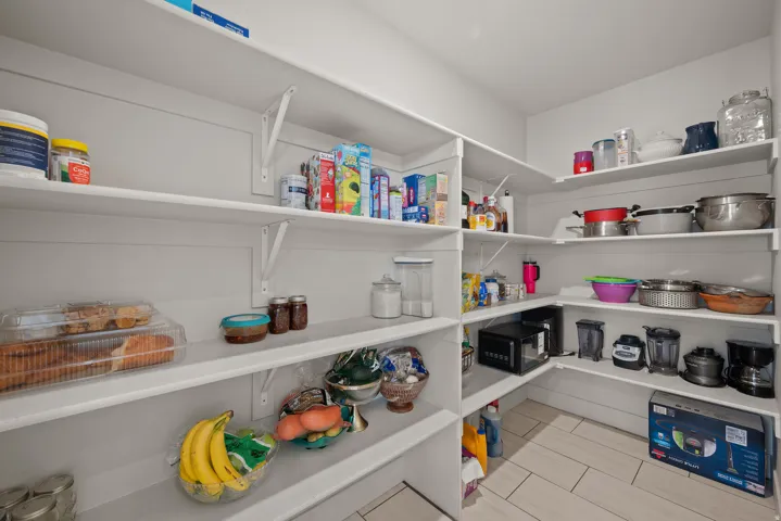 Expansive pantry with white shelving and tile flooring