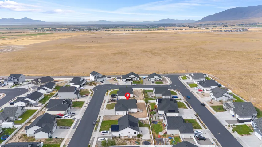 Residential development with newly paved streets and sidewalks, featuring multiple single-family homes with dark roofs and light-colored exteriors