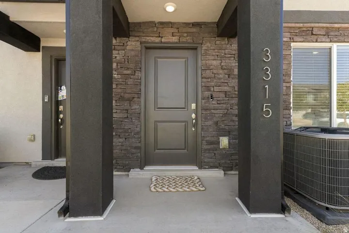 Entryway featuring a dark paneled door, stacked stone wall, and a concrete patio