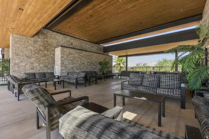 Expansive covered patio featuring a wood-panel ceiling, stone accent walls, and concrete flooring