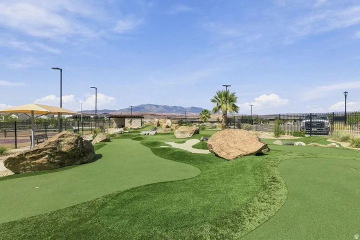Miniature golf course featuring artificial turf, decorative boulders, and palm trees