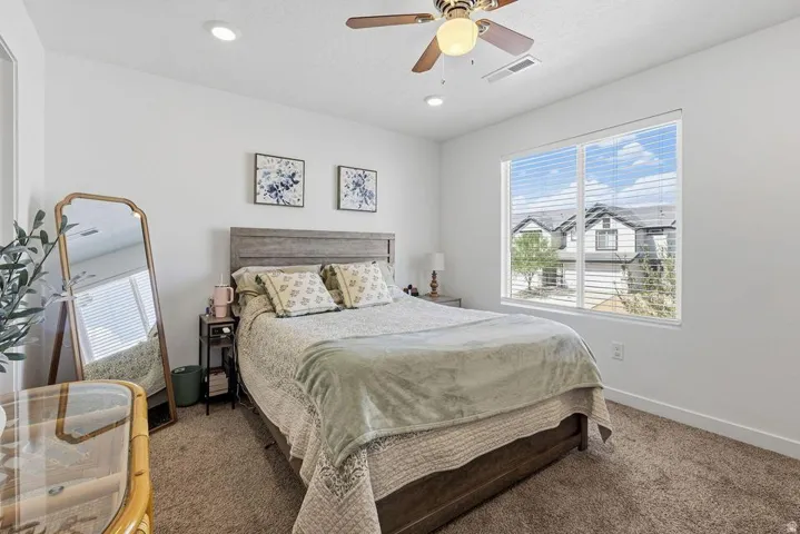 Recessed lighting, ceiling fan, large window with blinds, carpeted flooring, and a wood-finish headboard