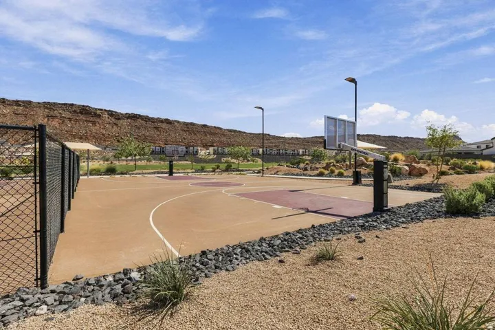 Multi-purpose court with two basketball hoops, fenced perimeter, and dedicated court lighting