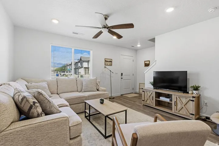 Wood-finish flooring, recessed lighting, ceiling fan, and white window blinds