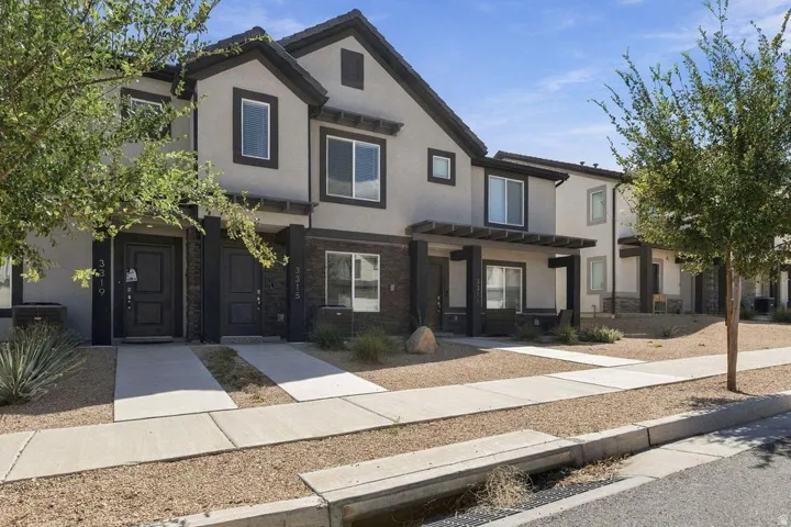 Stucco exterior with dark trim accents, covered entryways, and multiple windows