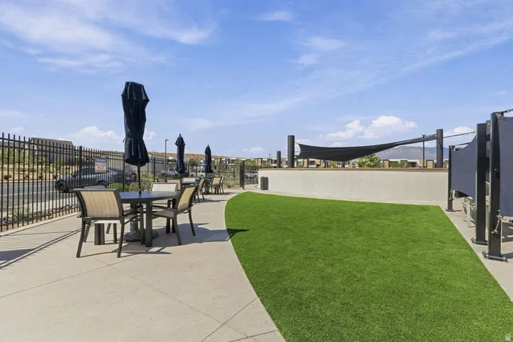 Paved patio area with outdoor seating, artificial turf section, and a partial shade structure