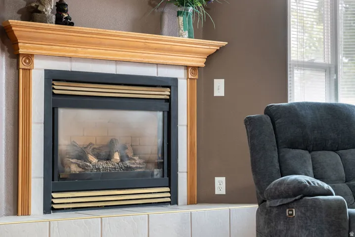 Fireplace with a wood mantle, tile surround, and a glass-front insert with faux logs