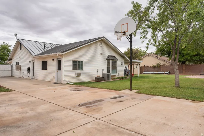 Exterior featuring white vinyl siding, a metal roof, a bay window, and a concrete driveway