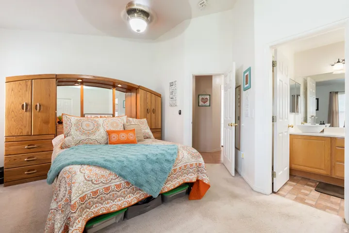 Carpeted room featuring a ceiling fan and an open doorway to a bathroom