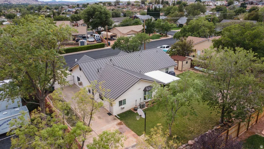 Exterior featuring a metal roof, mature trees, a detached storage shed, a paved driveway, and a fenced perimeter