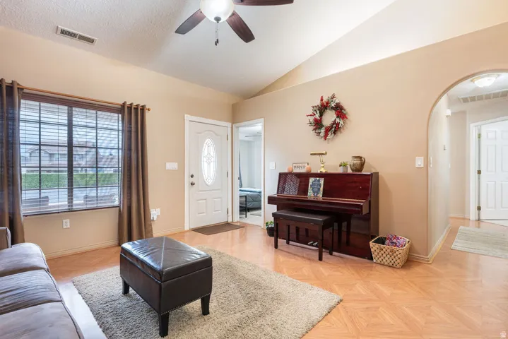 Vaulted ceilings, wood-finish flooring, and a ceiling fan create an inviting atmosphere