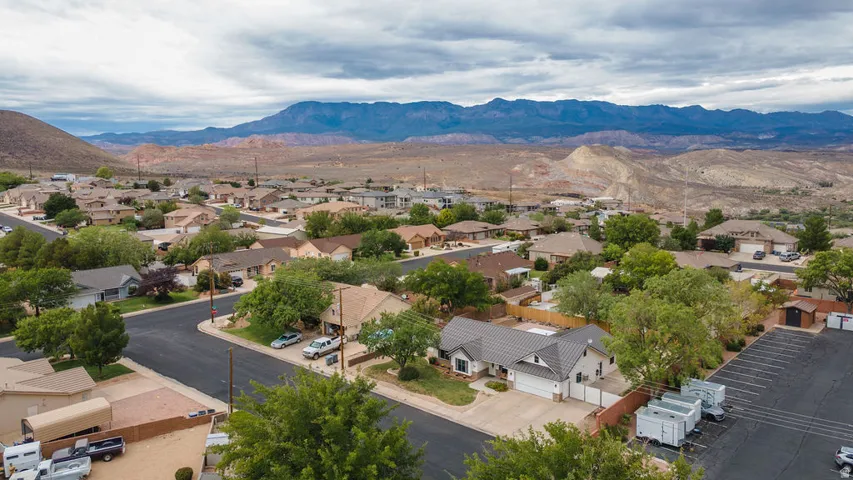 Residential neighborhood with mature trees and paved streets, framed by distant mountains and hills
