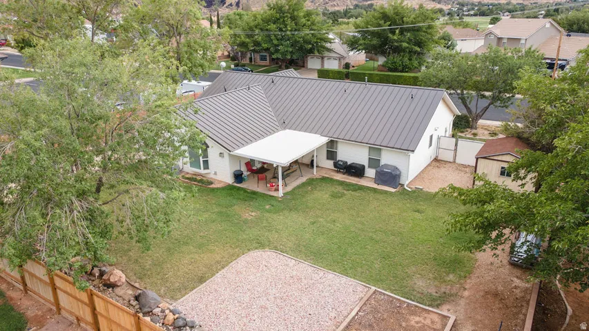 Expansive backyard featuring a manicured lawn, covered patio, metal roof, and wood fencing