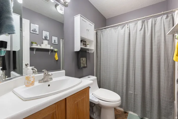 Bathroom featuring a single vanity with an integrated sink, brushed nickel faucet, and wood-finish cabinetry