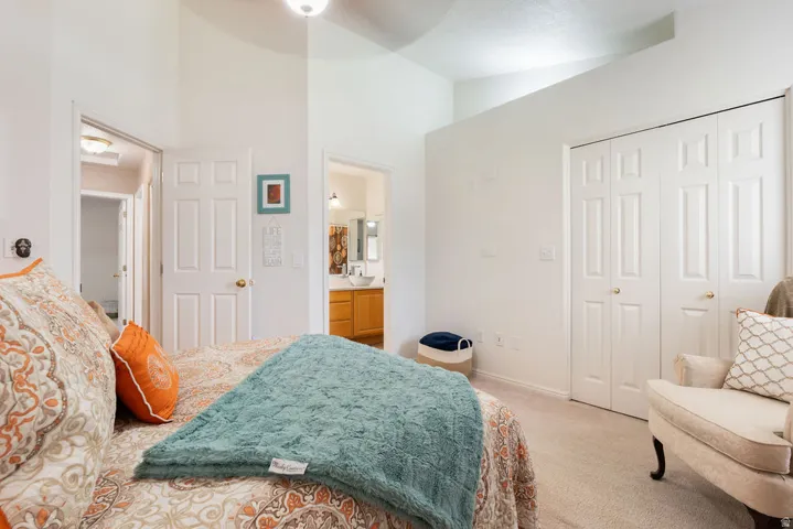 Vaulted ceiling, two paneled bi-fold closet doors, carpeted flooring, and a ceiling fan with light fixture
