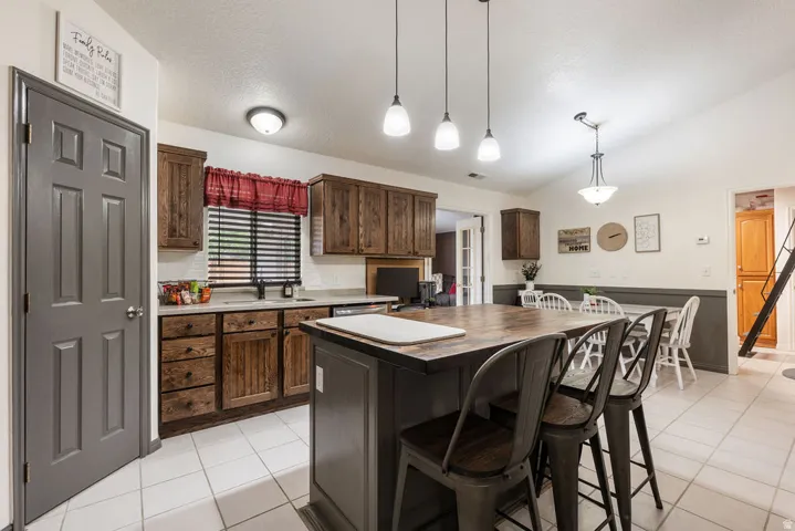 Kitchen featuring wood-finish cabinetry, a central island with seating, pendant lighting, and tiled flooring