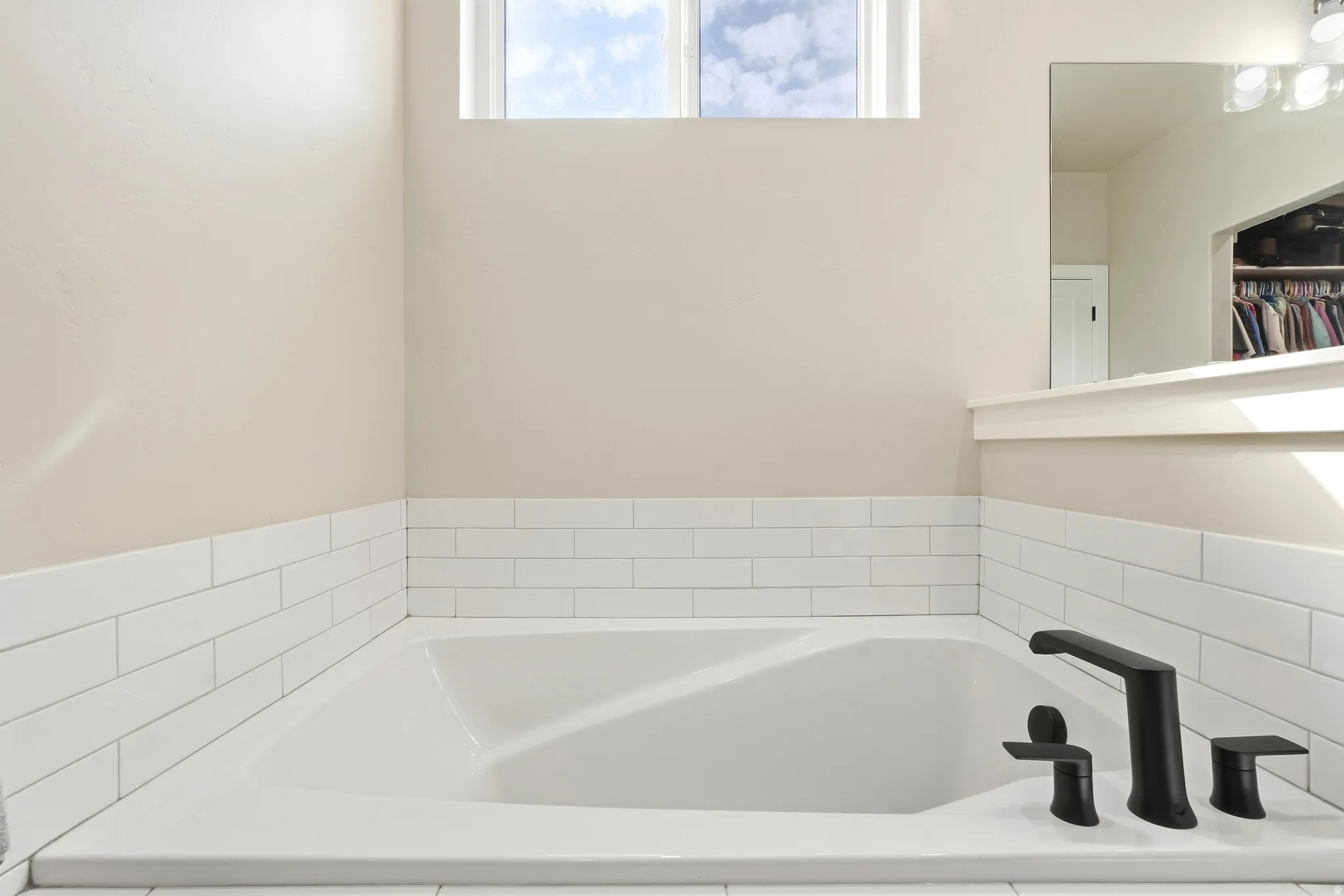 Built-in soaking tub with modern matte black fixtures and white subway tile surround