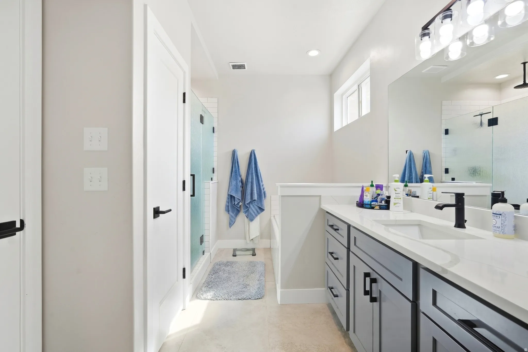 White countertop with undermount sink, dark gray cabinetry, and matte black fixtures