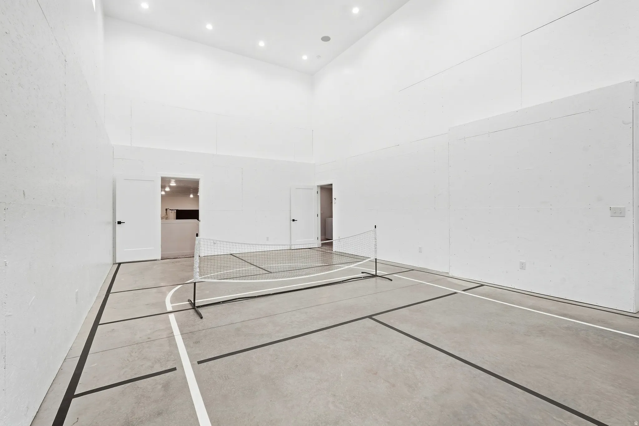 Indoor court with marked concrete flooring, high ceilings, and recessed lighting