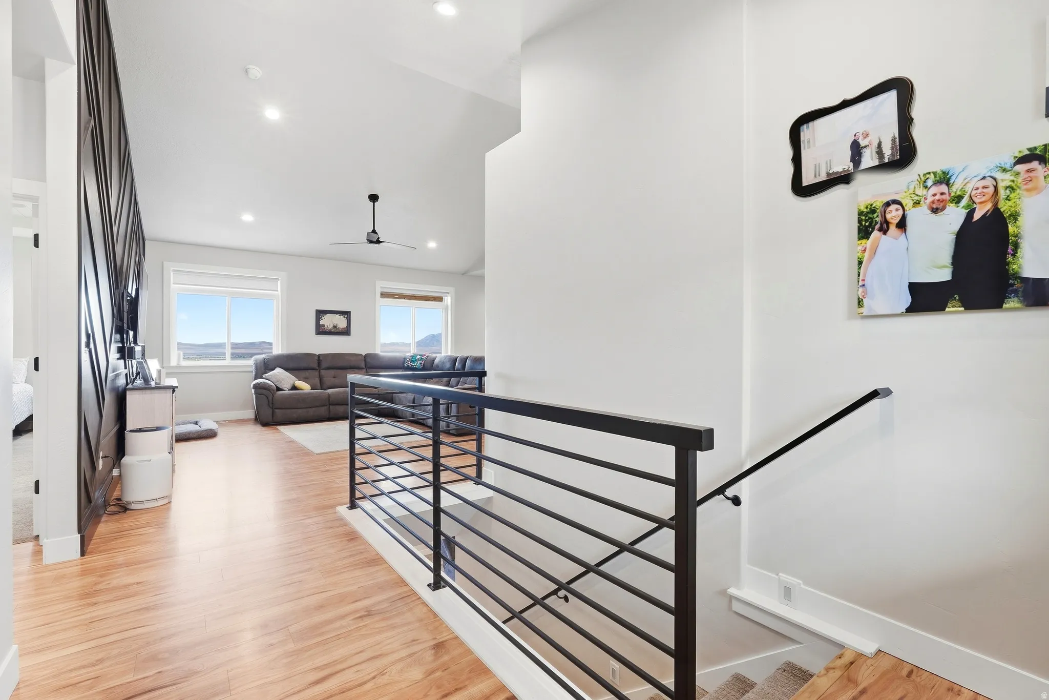 Vaulted ceilings, recessed lighting, wood-finish flooring, metal bar railing, and ceiling fan