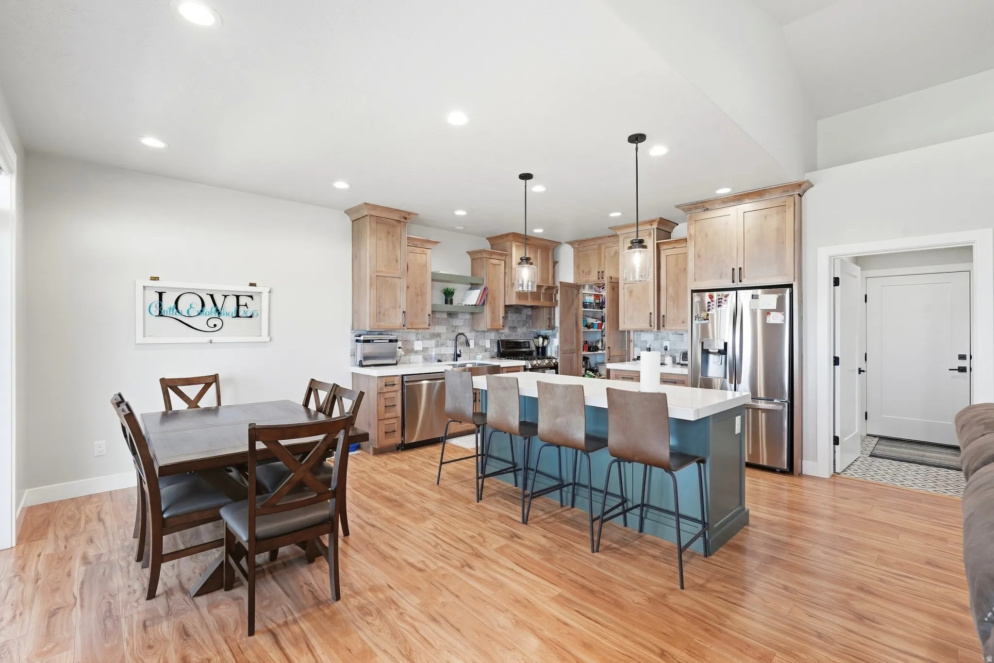 Light wood-finish flooring with a multi-tone kitchen island, stainless steel appliances, and recessed lighting