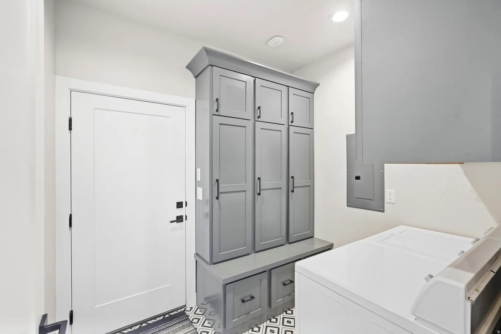 Integrated storage cabinetry with built-in bench, patterned floor tiling, and a flush-mounted ceiling light