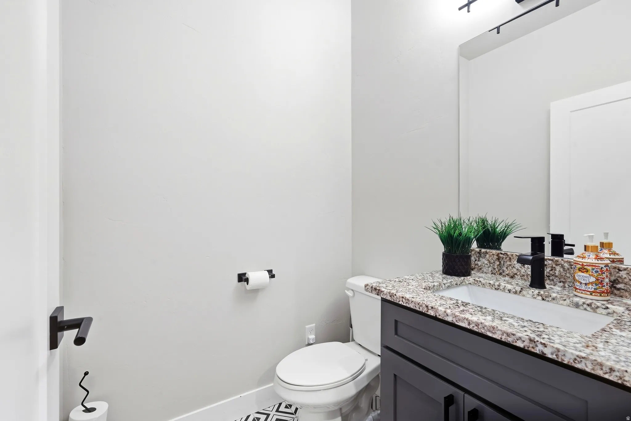 Black vanity with a stone countertop, under-mount sink, and matte black faucet