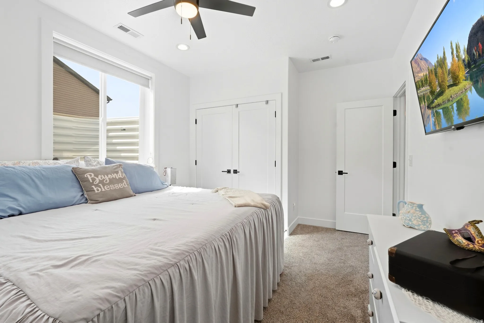 Recessed lighting, ceiling fan, white paneled doors with black hardware, and carpeting