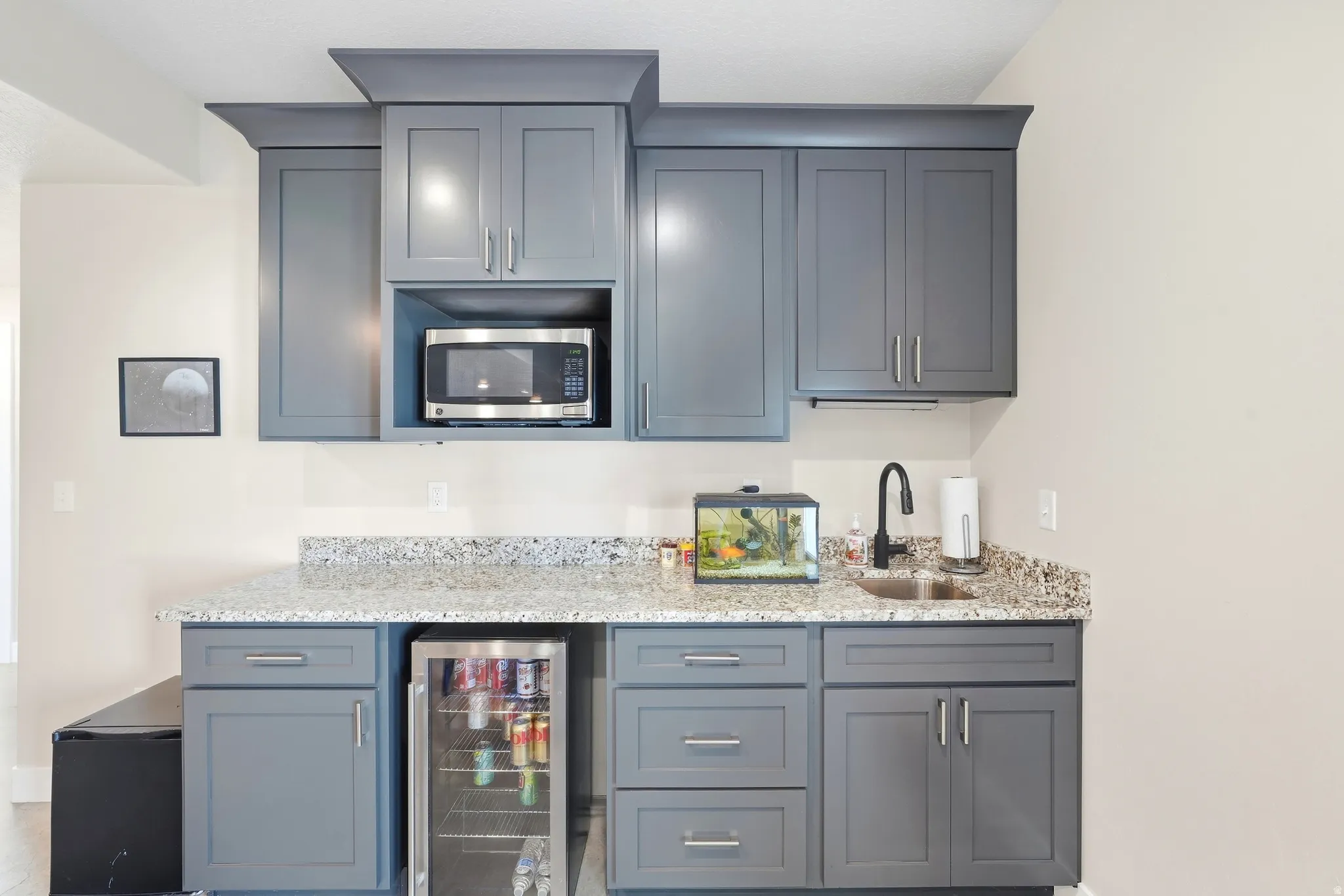 Built-in cabinetry with a stone-finish countertop, undermount sink, and beverage refrigerator