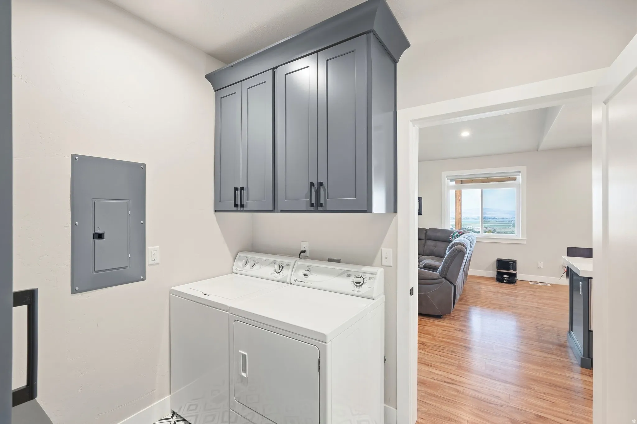 Laundry area with overhead gray cabinetry, black hardware, and patterned floor tile