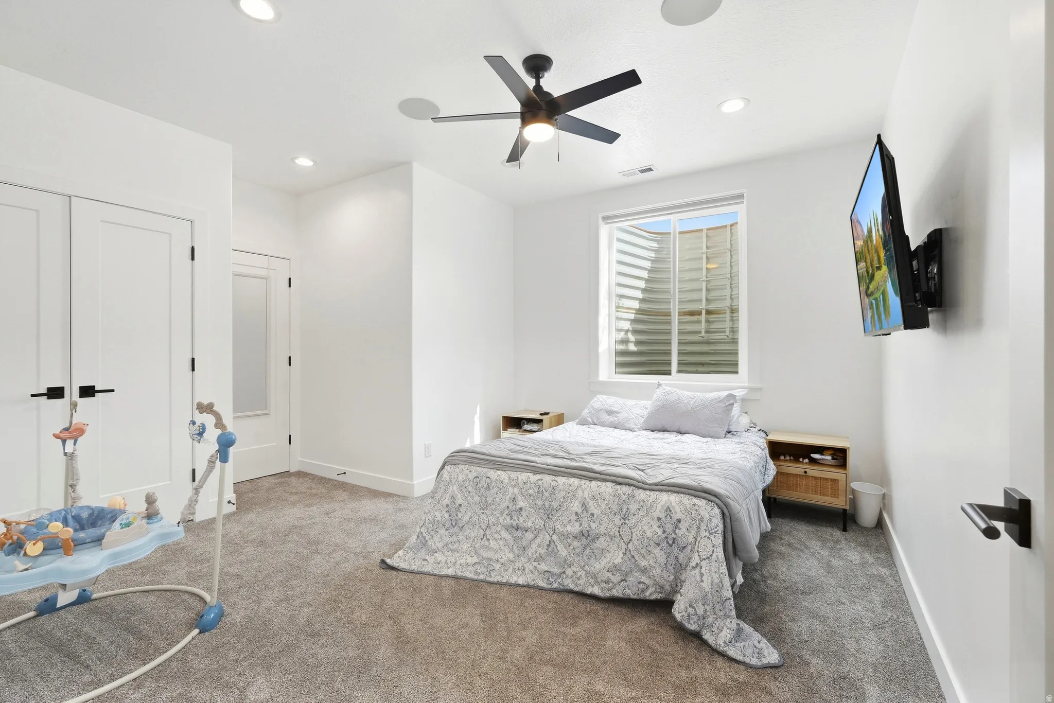 Recessed lighting, ceiling fan, white paneled doors with black hardware, and an egress window