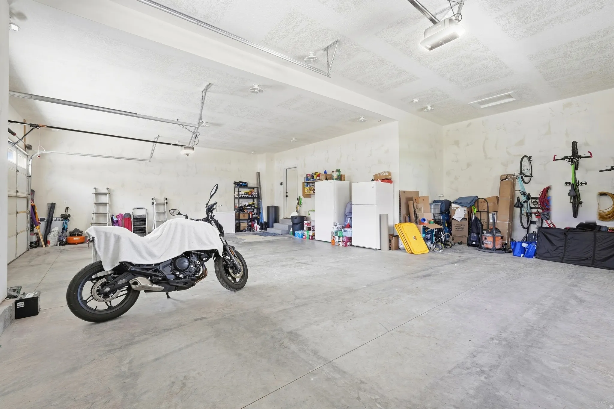 Spacious garage with concrete flooring, overhead lighting, and white walls