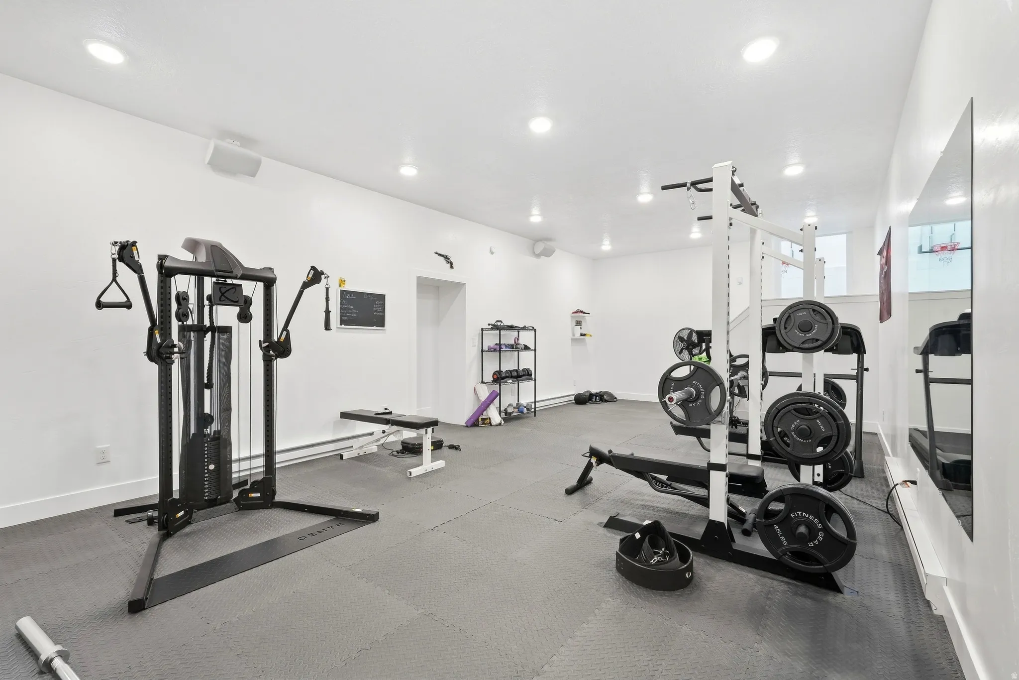 Recessed lighting with a white ceiling, white walls, and gray interlocking floor mats