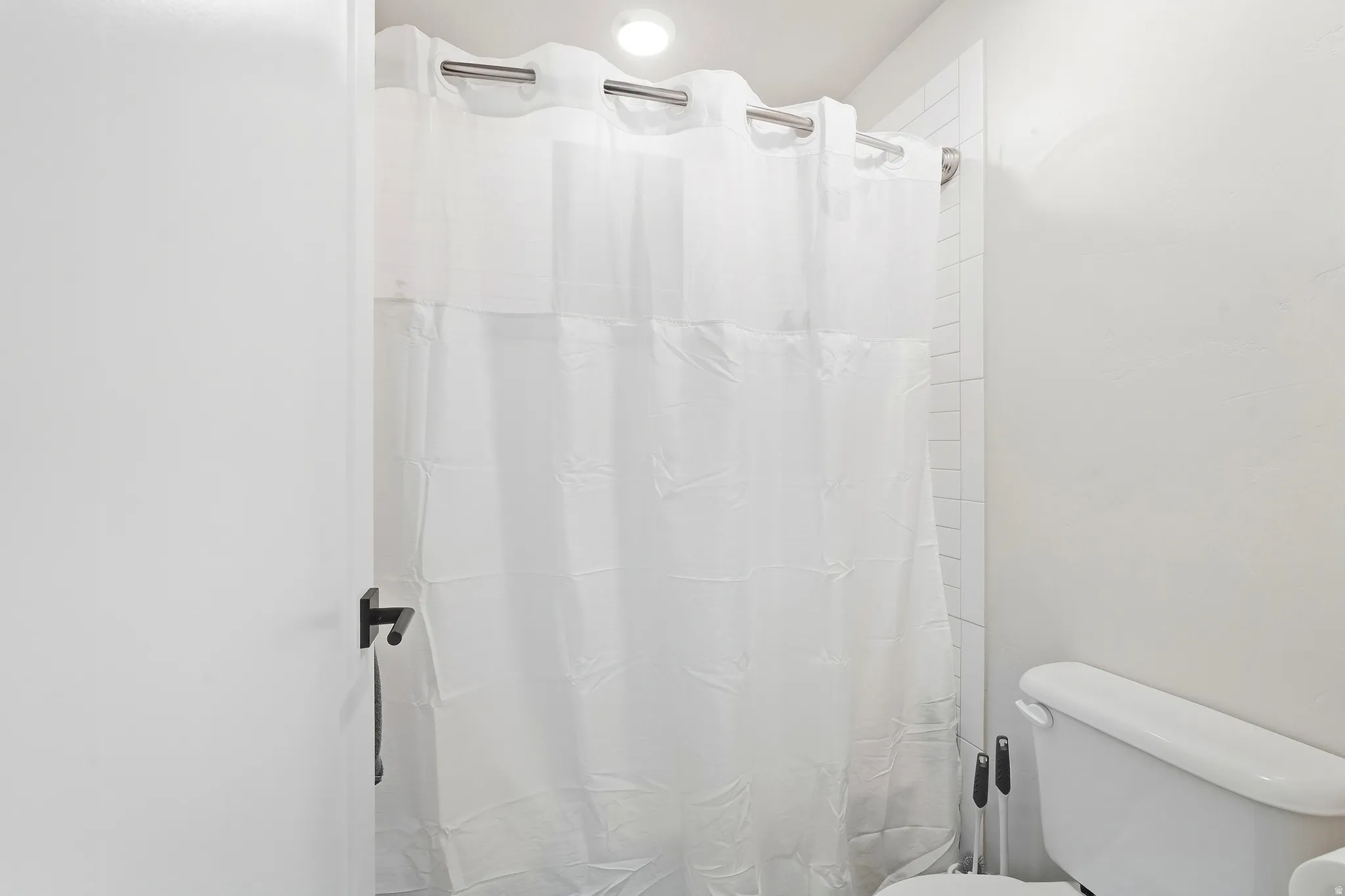 Recessed ceiling lighting illuminates the vertical subway tile shower surround