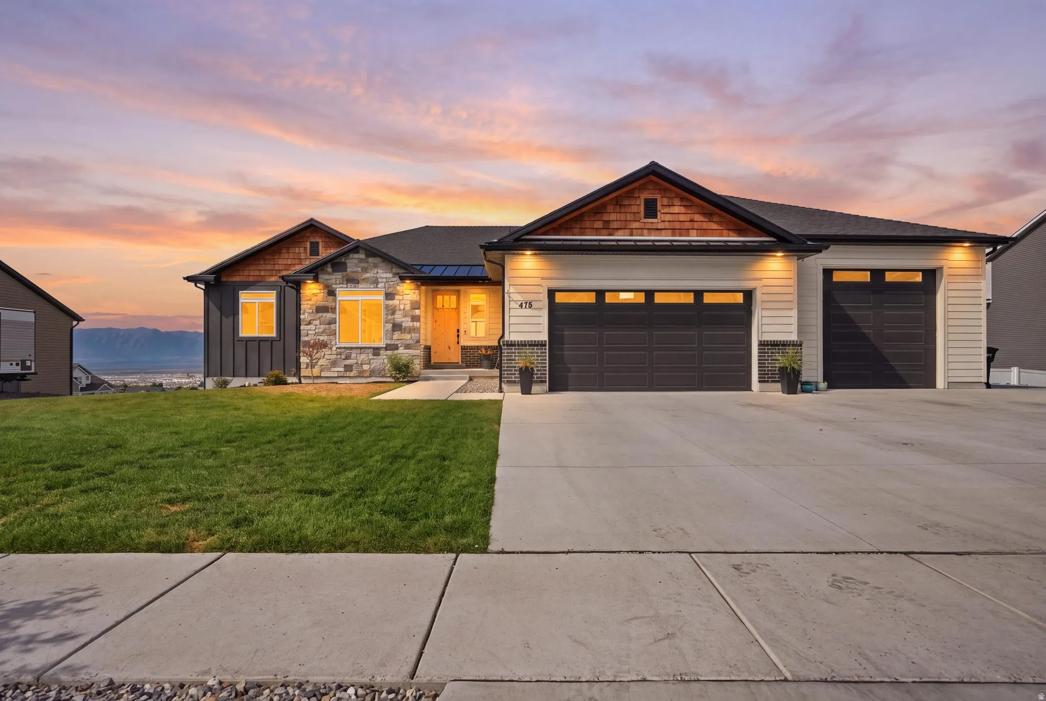 Stone facade accenting, two-car garage, single garage bay, concrete driveway, and front lawn