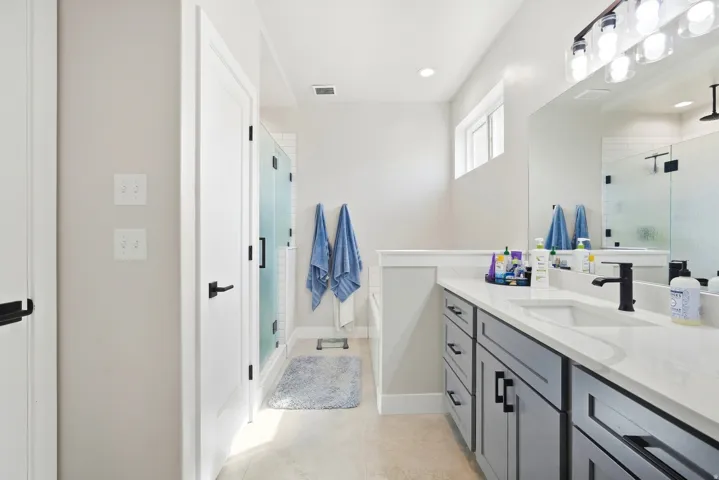 White countertop with undermount sink, dark gray cabinetry, and matte black fixtures