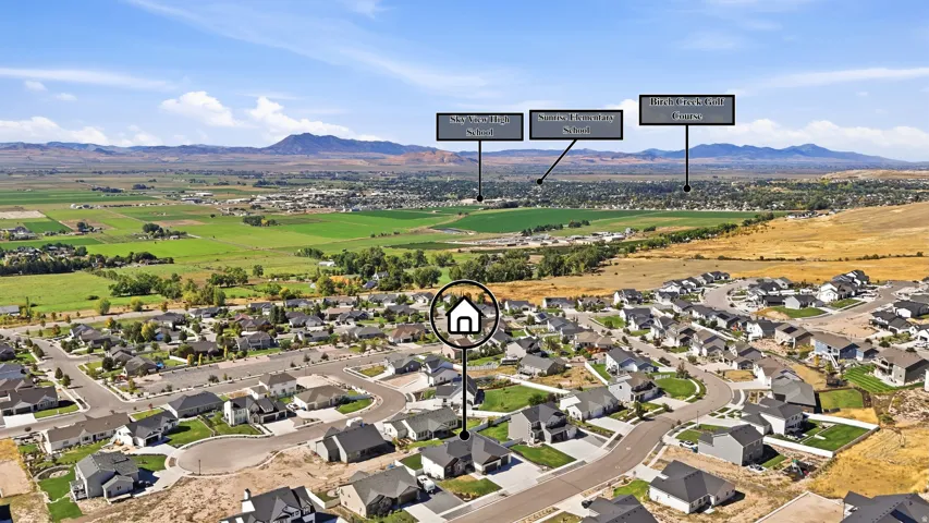 Aerial perspective showcasing a residential neighborhood with surrounding open fields and distant mountains